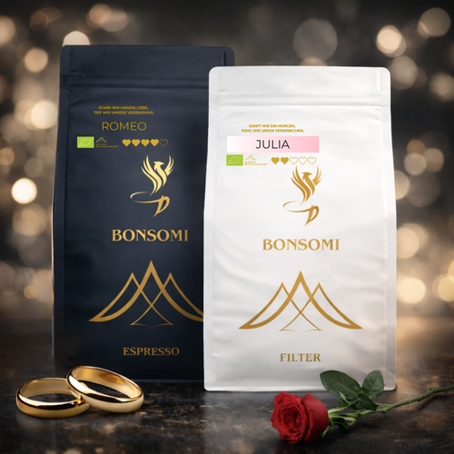 Zwei BONSOMI Kaffeepackungen in Weiß und Dunkelblau ohne Etiketten, arrangiert vor dunklem Bokeh-Hintergrund mit goldenen Ringen und roter Rose.